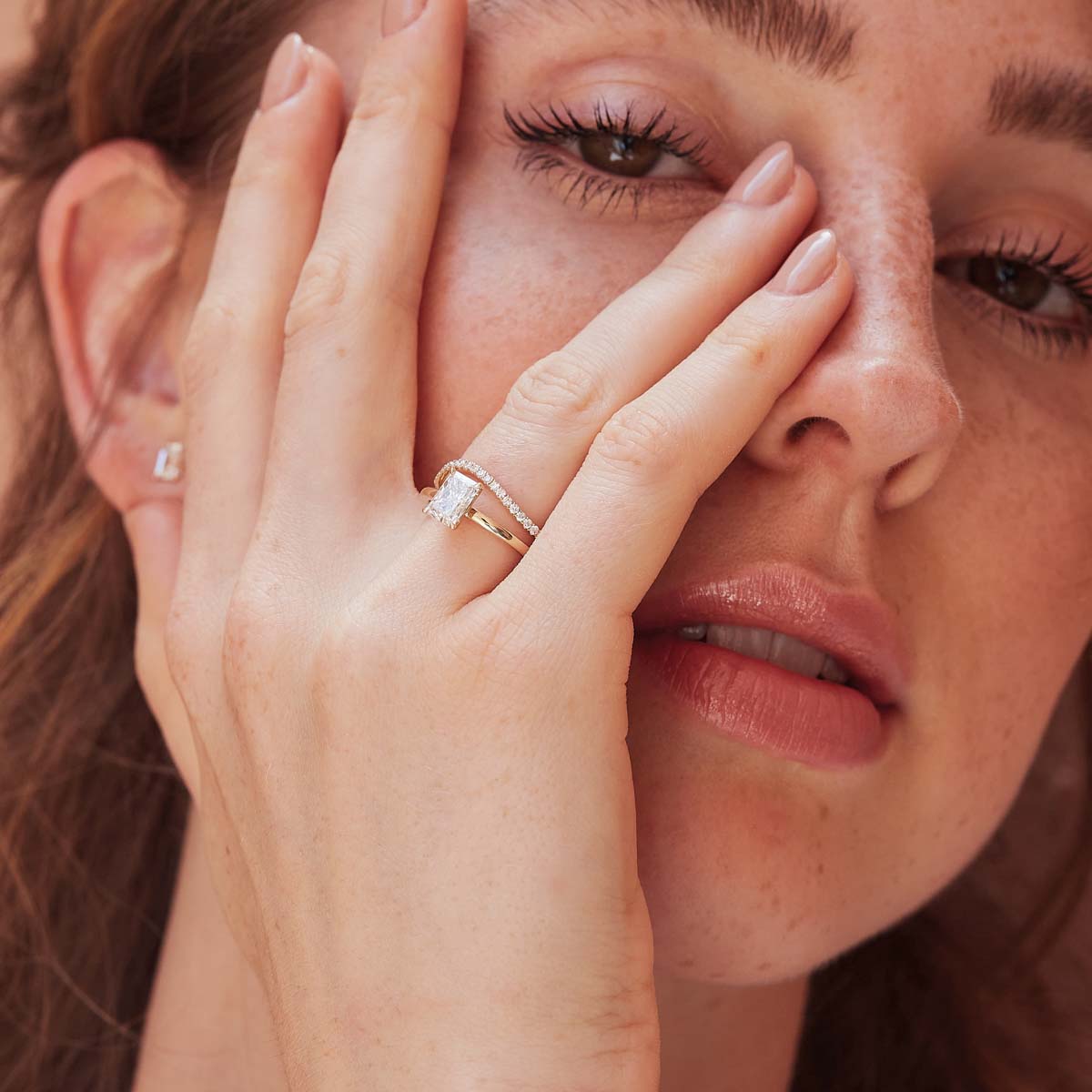 Model trägt Radiant-Verlobungsring mit großem Lab-Diamanten in Gelbgold