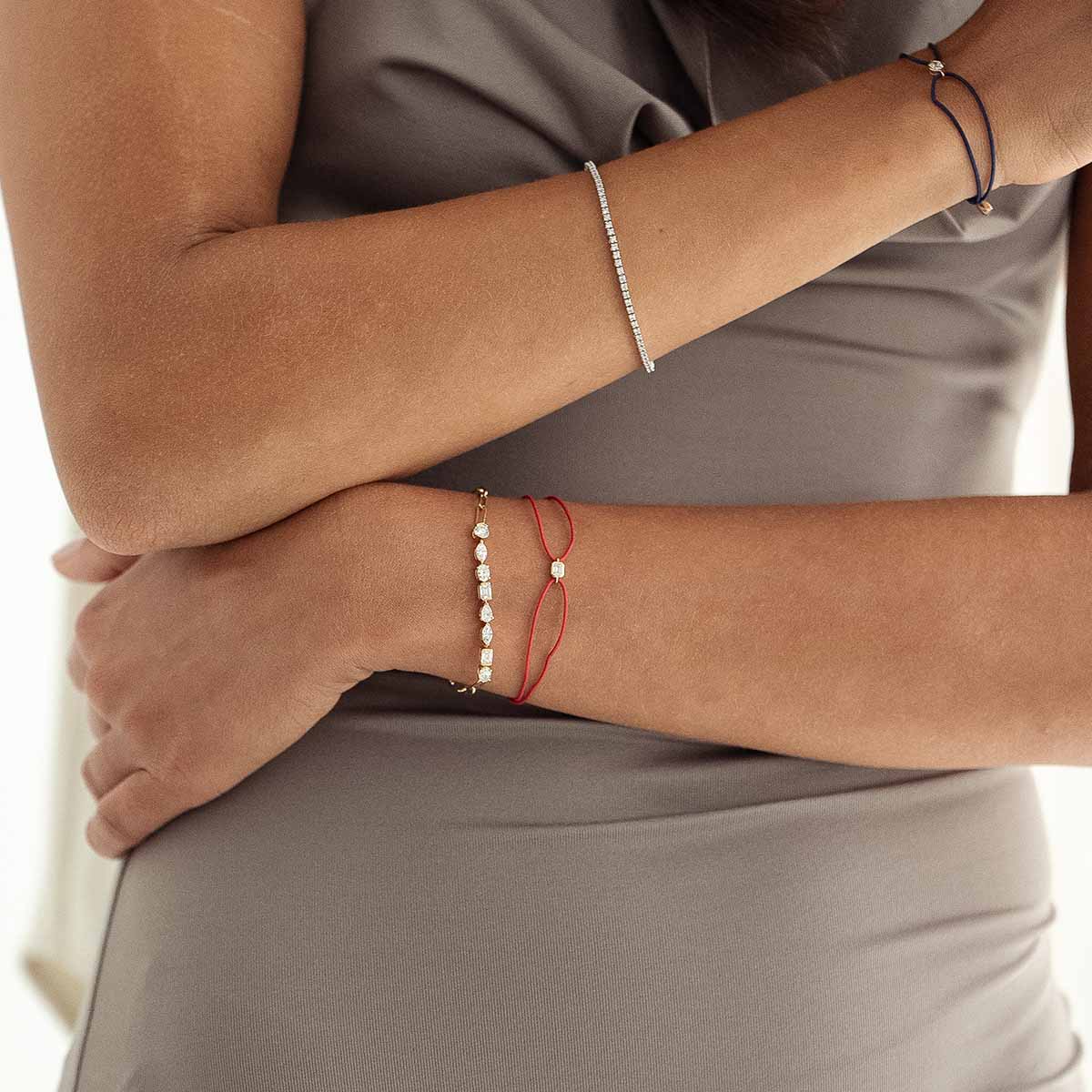 Model trägt rotes Kordelarmband in Kombination mit Diamantarmband