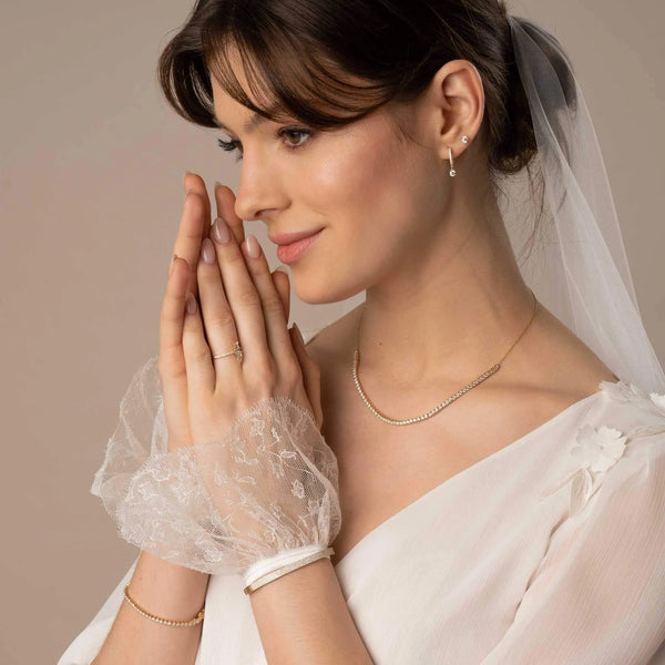 Braut trägt schönen Hochzeitsschmuck- Ohrringe, Kette, Verlobungsring und Armband mit labor-kultivierten Diamanten