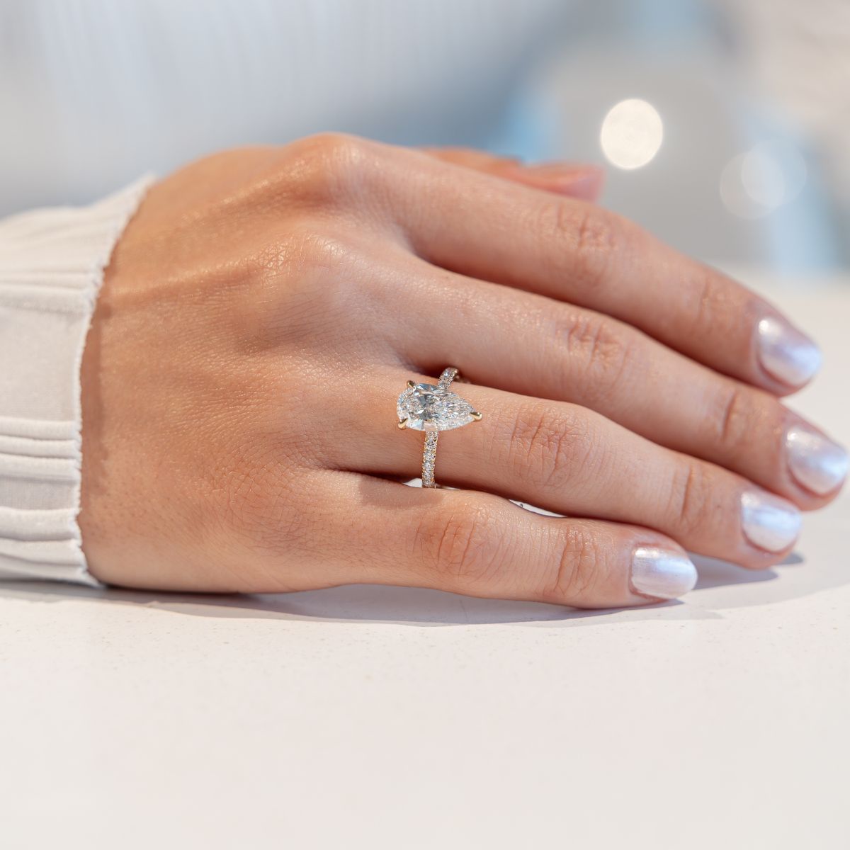 Model trägt gelbgoldenen Verlobungsring mit Labor Diamant im Pearschliff