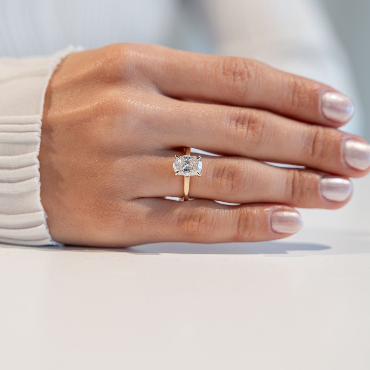 Model trägt gelbgoldenen Verlobungsring mit Labor Diamant im Cushion -Schliff