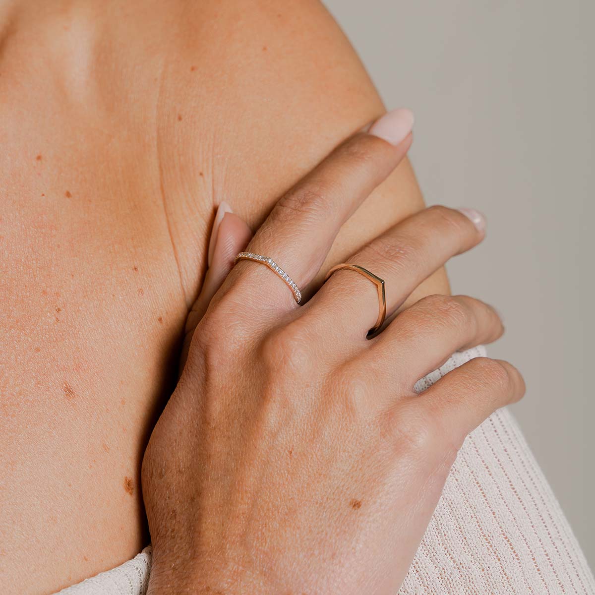 Model trägt zwei Tropfenförmige Ringe an zwei nebeneinanderliegenden Fingern. Einer davon ist mit runden Labor Diamanten besetzt der andere ist aus reinem Gold.