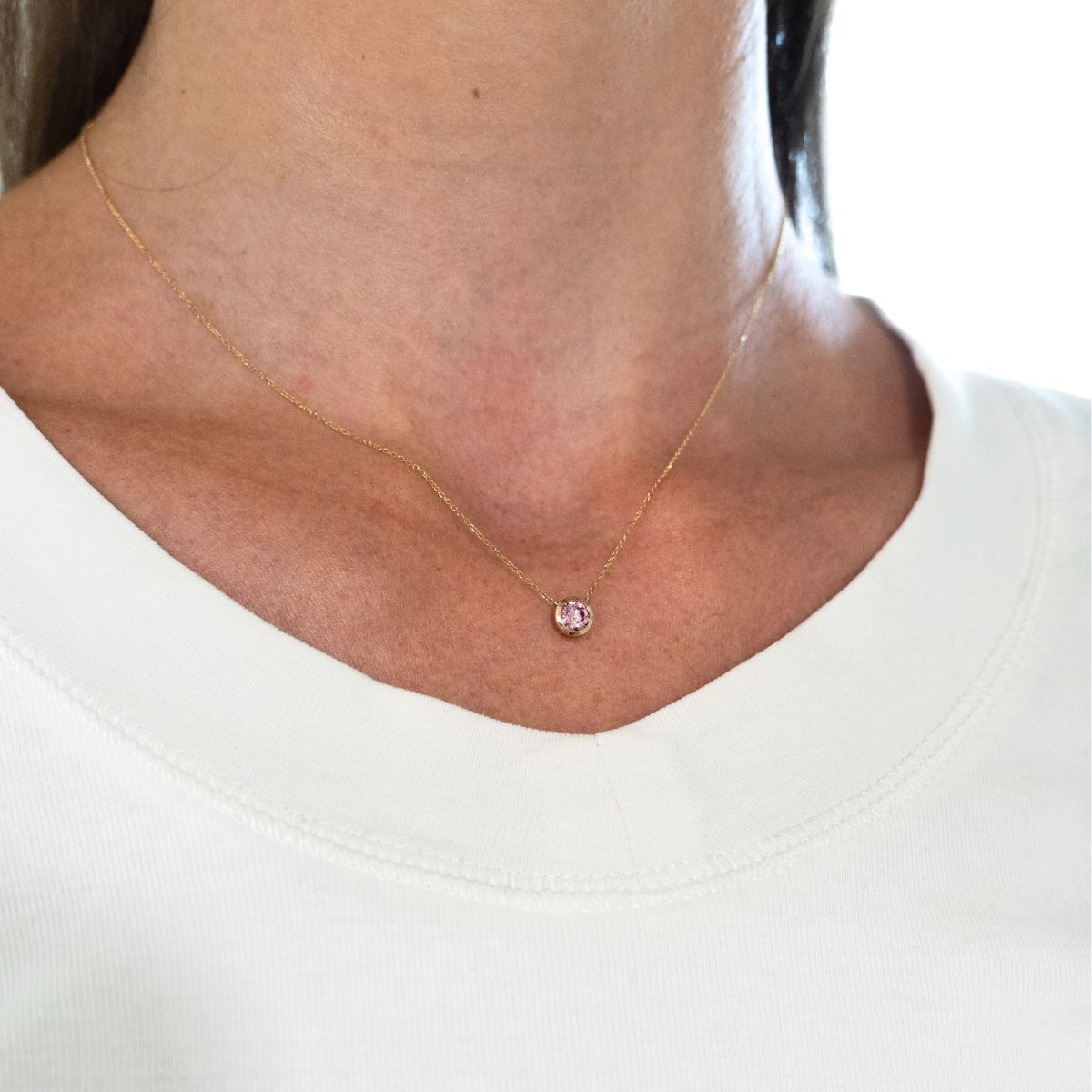 Nahaufnahme einer Halskette mit einem runden, pinken 0.5ct Stein an einem Hals getragen.