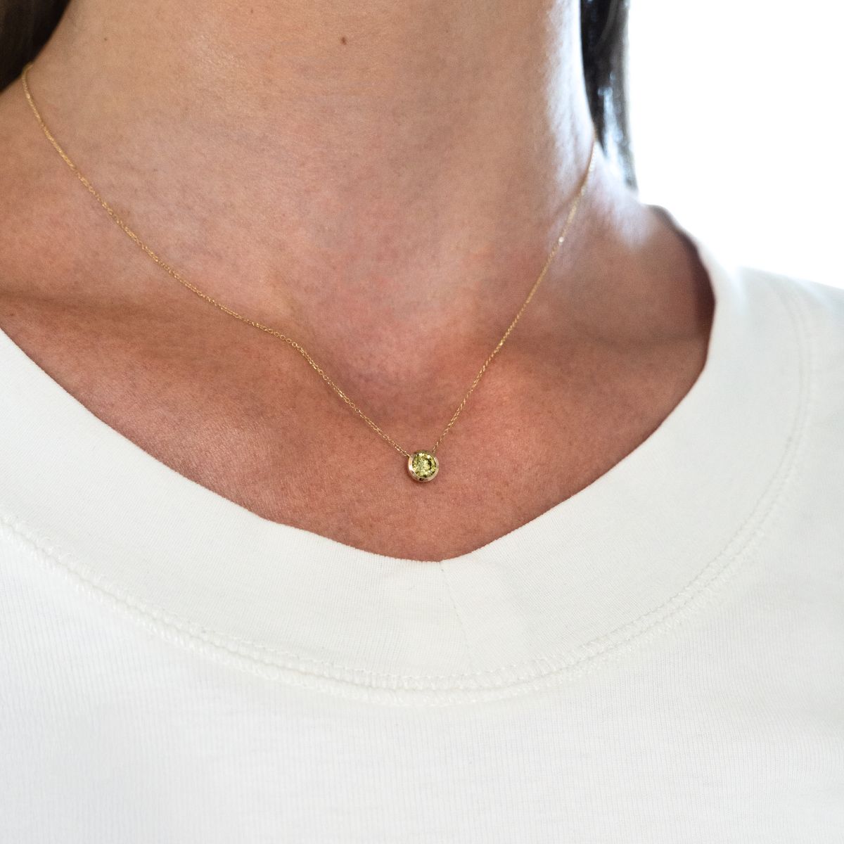 Nahaufnahme einer Halskette mit einem runden, gelbem 0.5ct Stein an einem Hals getragen.