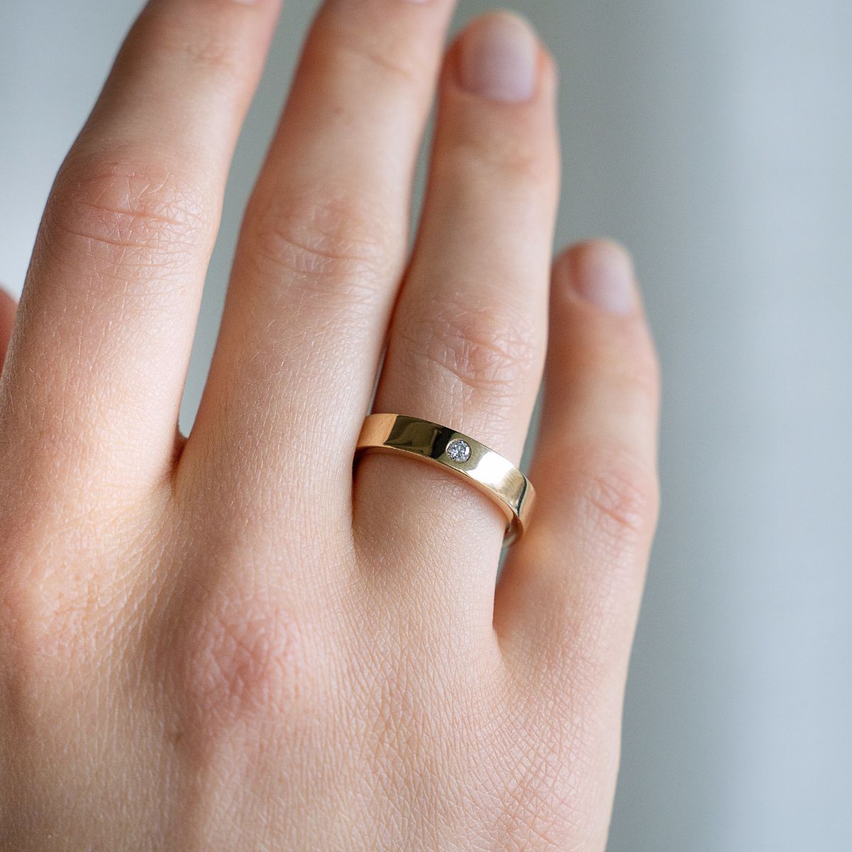 Model trägt Ehering aus Gelbgold mit kleinem Lab Diamanten im Rundschliff