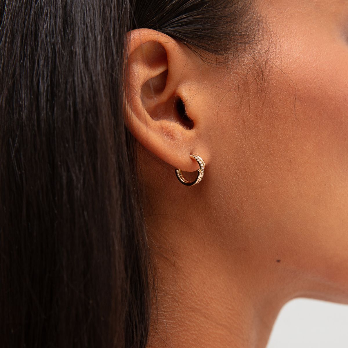 Model trägt Helix Ohrringe in Gold mit Diamanten am Ohr