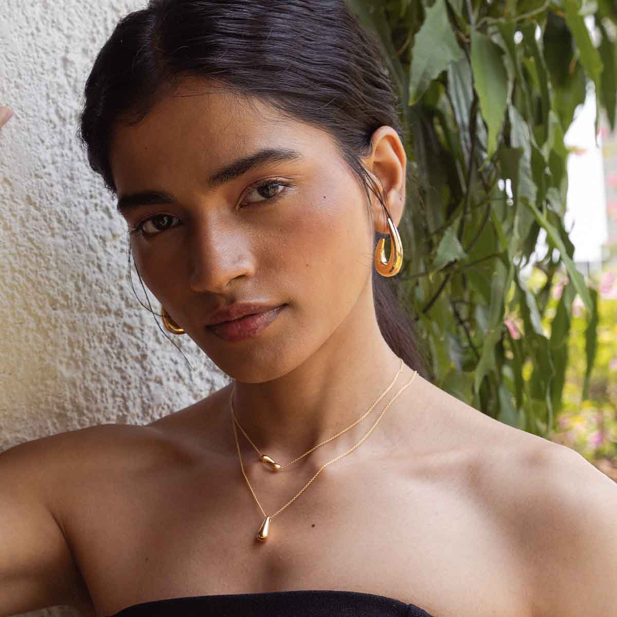 Frau trägt breite Halbkreolen 18k vergoldet in Gold