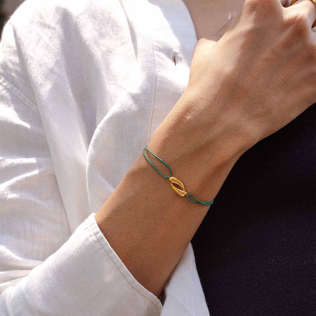 Grünes Kordarmband mit 18k vergoldetem Anhänger getragen