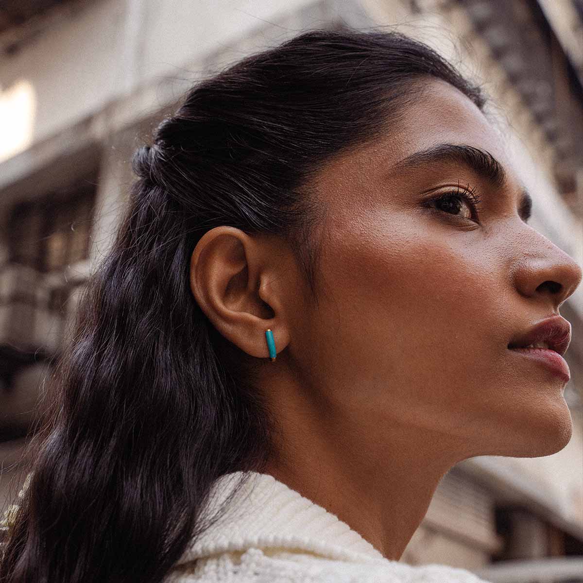 Model trägt U-förmige Kreolen in Gelb mit farbigem Detail am Ohr und schaut zur Seite