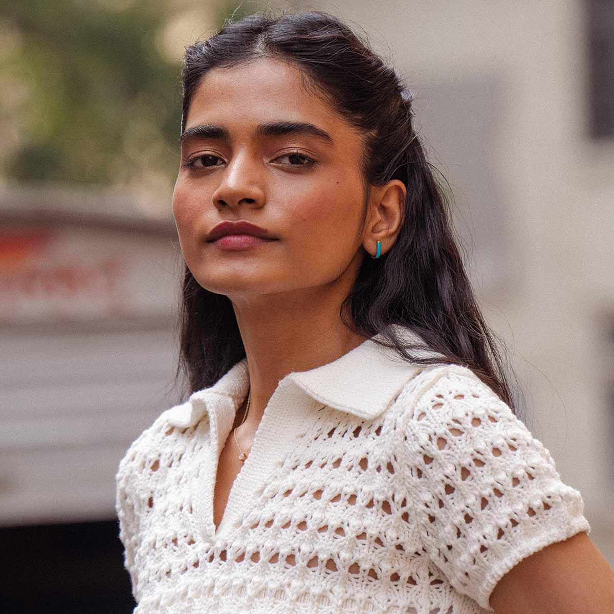 Model trägt U-förmige Kreolen in Türkis und blickt selbstbewusst in die Kamera