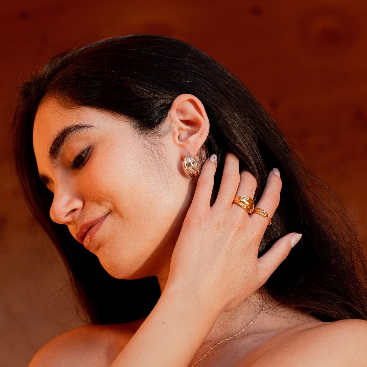 Model trägt silberne Halbkreolen und zwei goldene Ringe