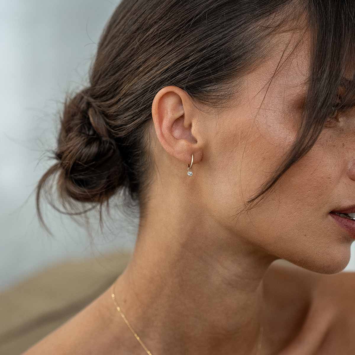 Model von Seite mit Diamantohrringen in Gold