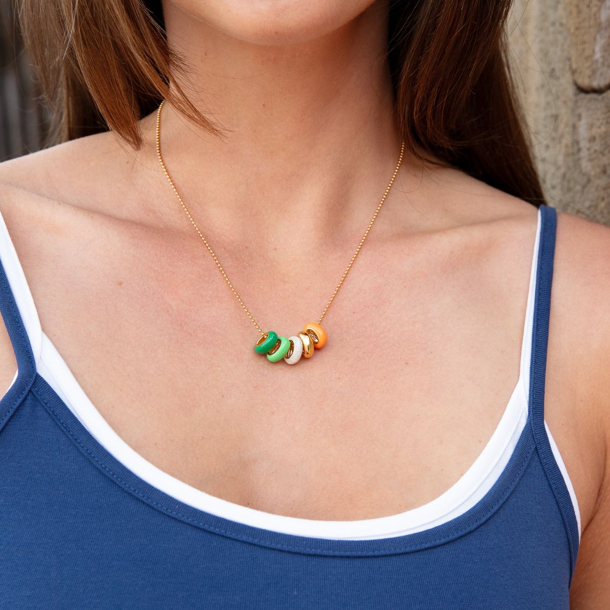 Model trägt eine Gelbgoldkette mit bunten Rondellen – Nahaufnahme.