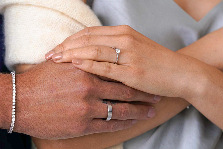 Ein Mann trägt Tennis Armband mit Lab Diamanten und schönen Ehering mit Weißgold und eine Frau trägt schönen Verlobungsring mit lab-kultivierten Diamanten