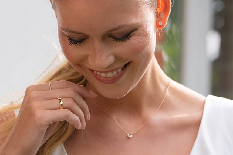 Model trägt schönen golden Ehering und Kette und Ohrringe mit Lab Diamanten