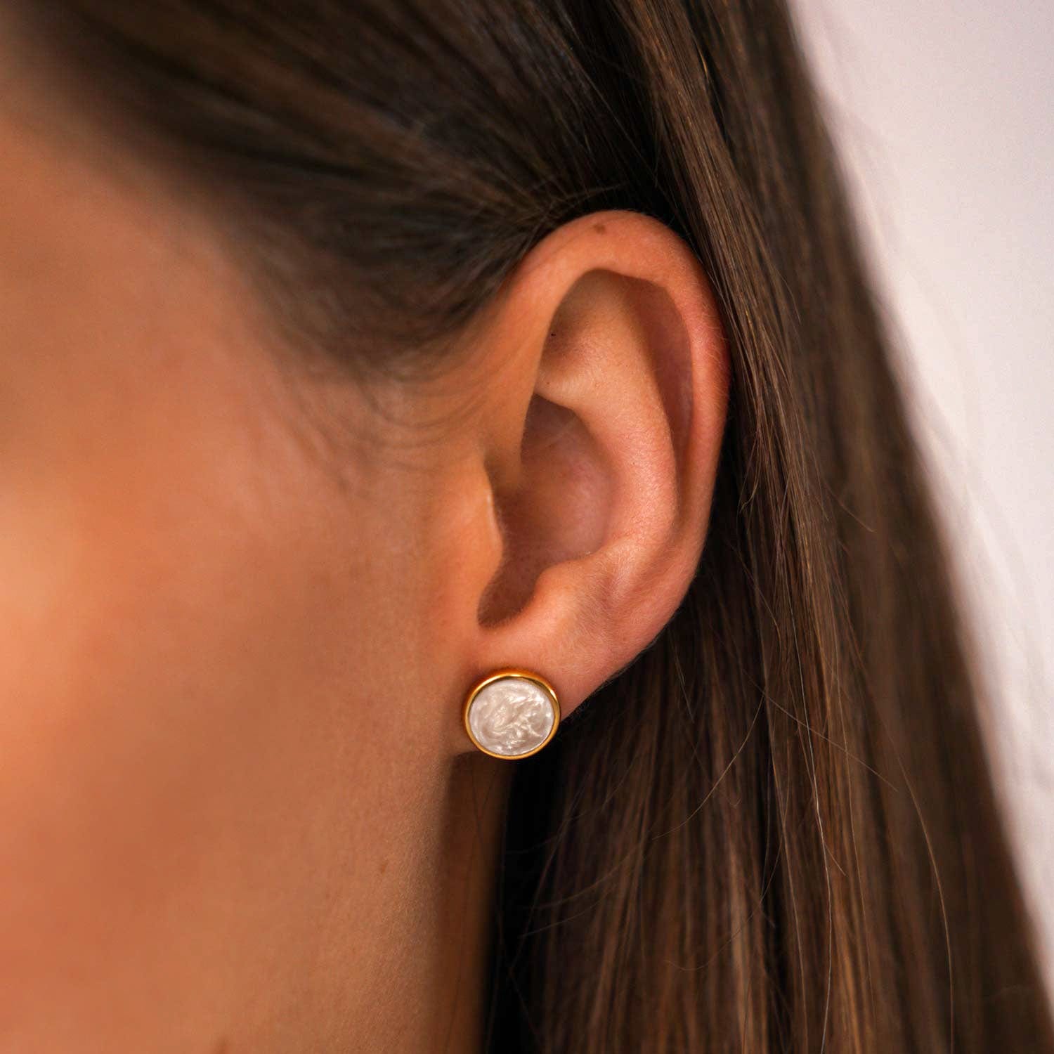 Model trägt goldenen Ohrstecker mit Perlweissem Disc