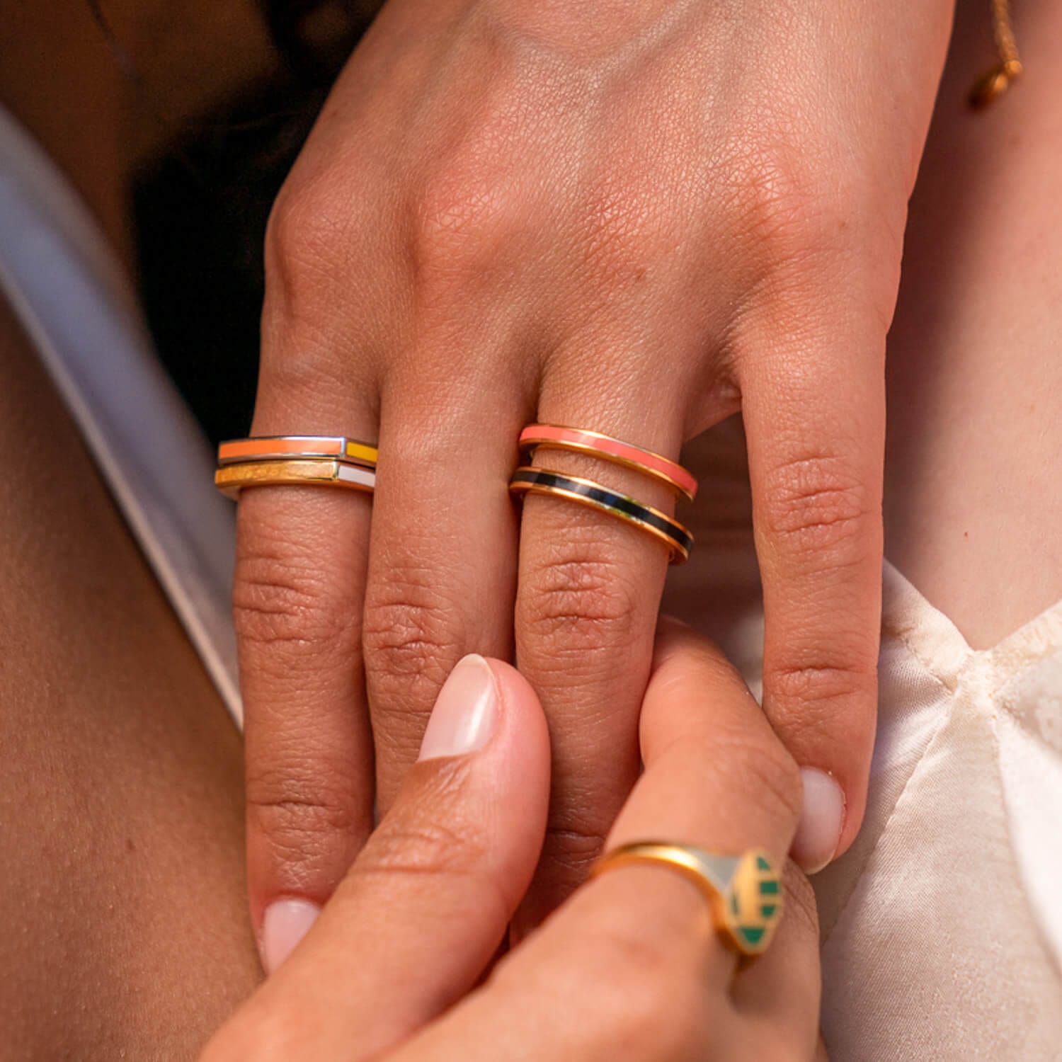 Model trägt zwei zusammen gesteckte Ringe an der Hand in sommerlichen Farben