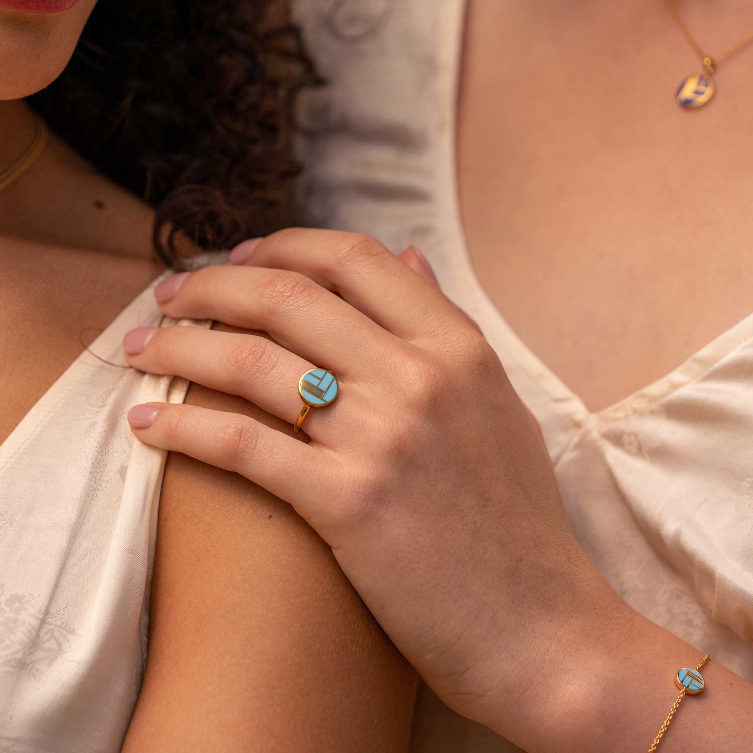 Hand eines Models mit goldenem Keramikring und Hellblauen Detail