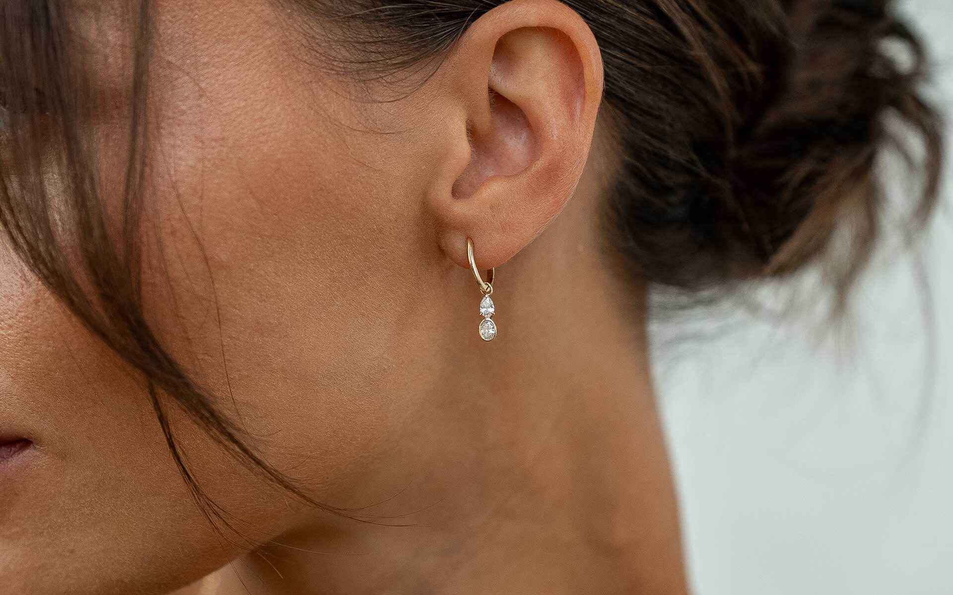 Model trägt zarten Diamantohrring in Ovalschliff