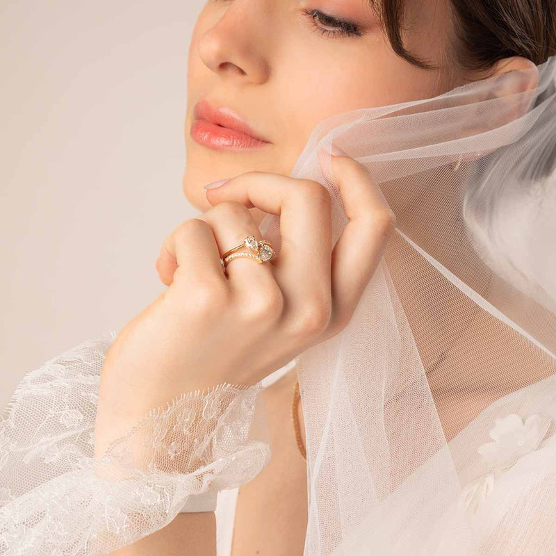 Brautmodel hält ihren Schleier und trägt einen Zwei-Stein-Diamantring