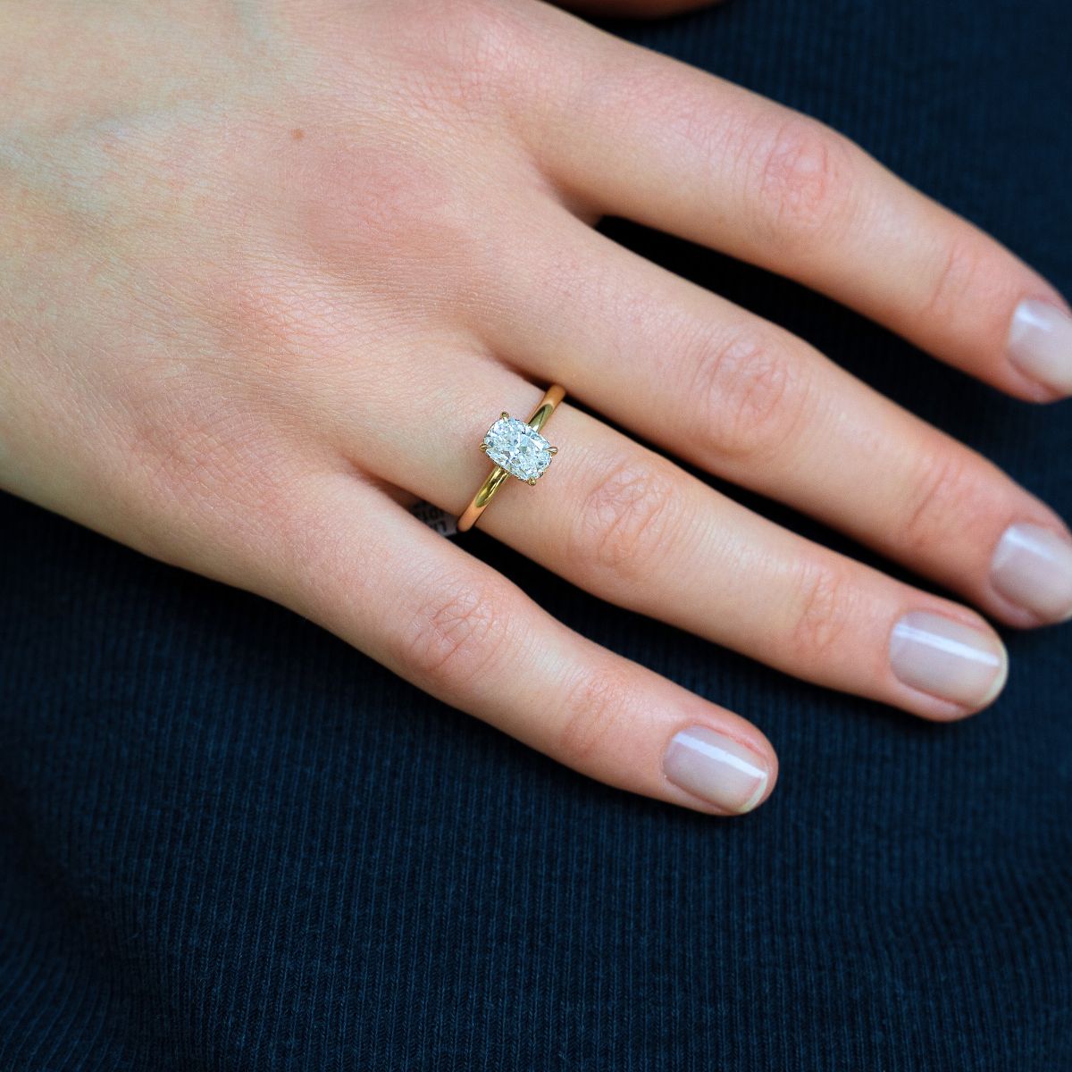 Model trägt Verlobungsring aus Gelbgold mit Lab Diamant im Elongated Cushion-Schliff und Halo aus kleinen Diamanten