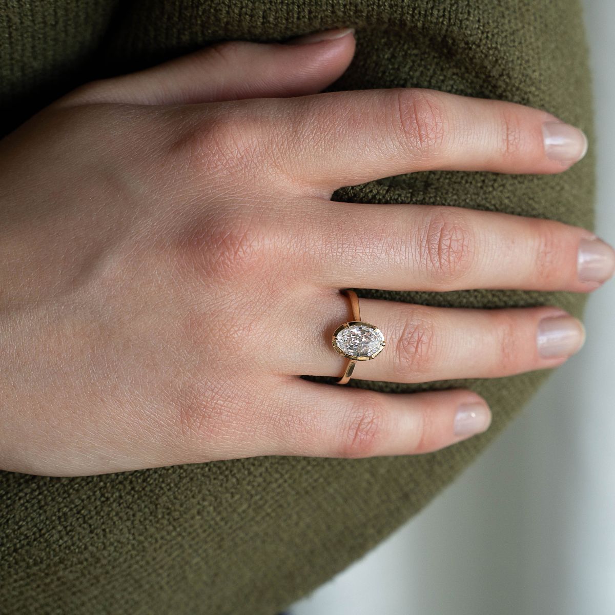 Model trägt Verlobungsring aus Gelbgold mit Lab Diamant im Moval-Schliff, zentrale Fassung