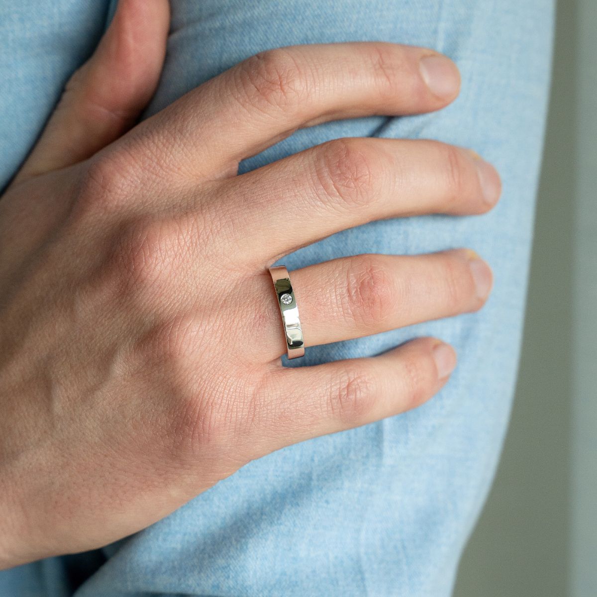 Model trägt Ehering aus Weissgold mit kleinem Lab Diamanten im Rundschliff