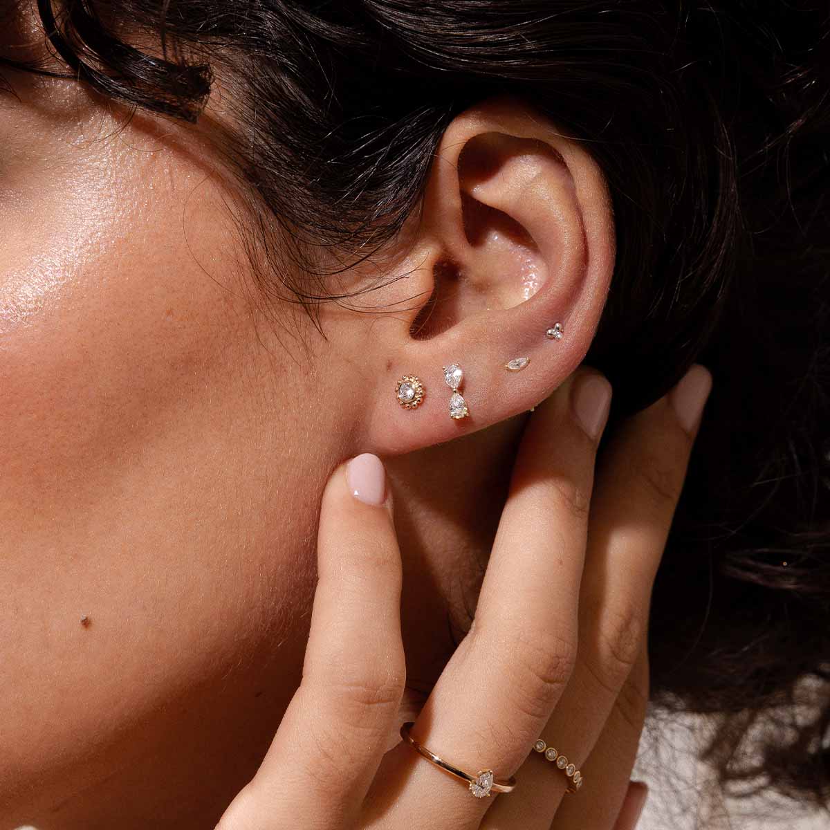 Ohr mit vier kleinen und großen Piercings mit Diamanten