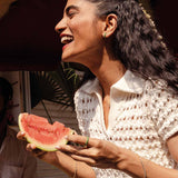 Frau lacht während sie eine Wassermelone in der Hand hält mit Keramikschmuck