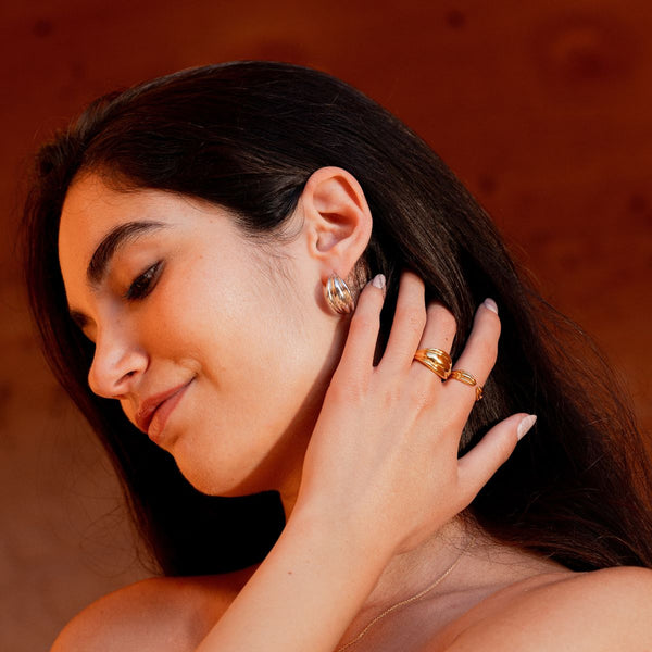 Model trägt silberne Halbkreolen und zwei goldene Ringe