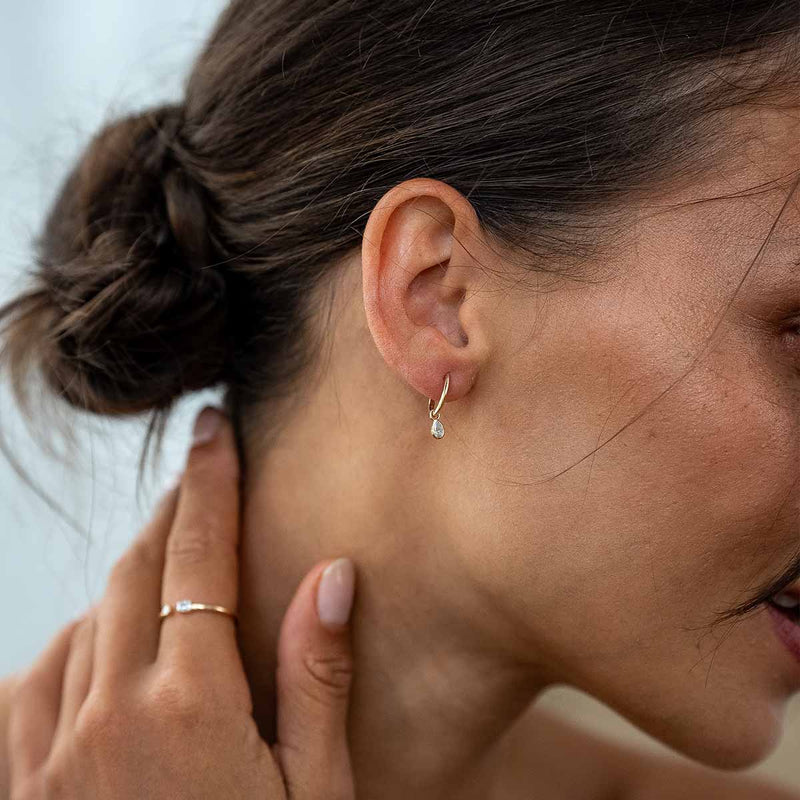 Model trägt goldene Ohrringe mit Lab Diamanten in Tropfenschliff