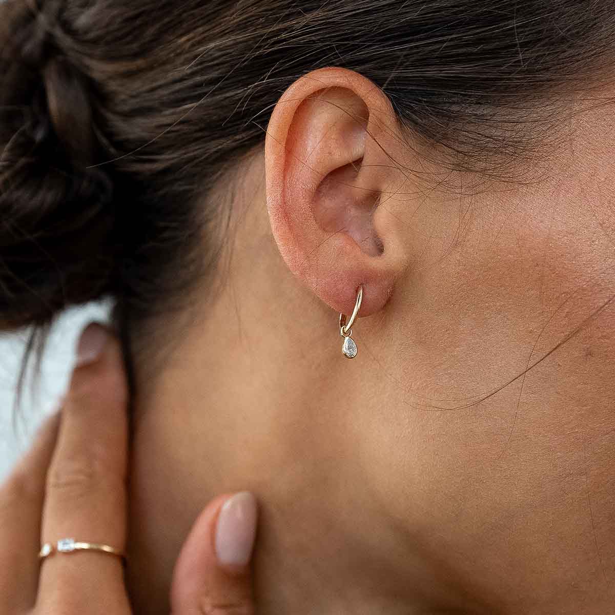 Model trägt goldenen Ohrhänger mit Lab Diamanten in Birnenschliff