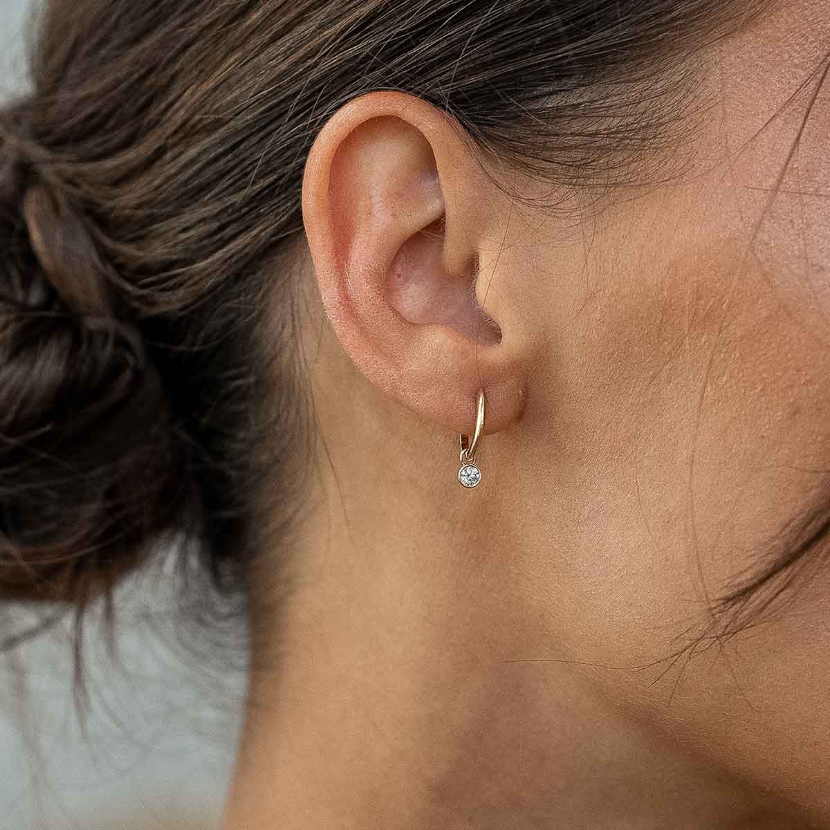 Model trägt Ohrring mit rundgeschliffenen Lab Diamanten in Gelbgold