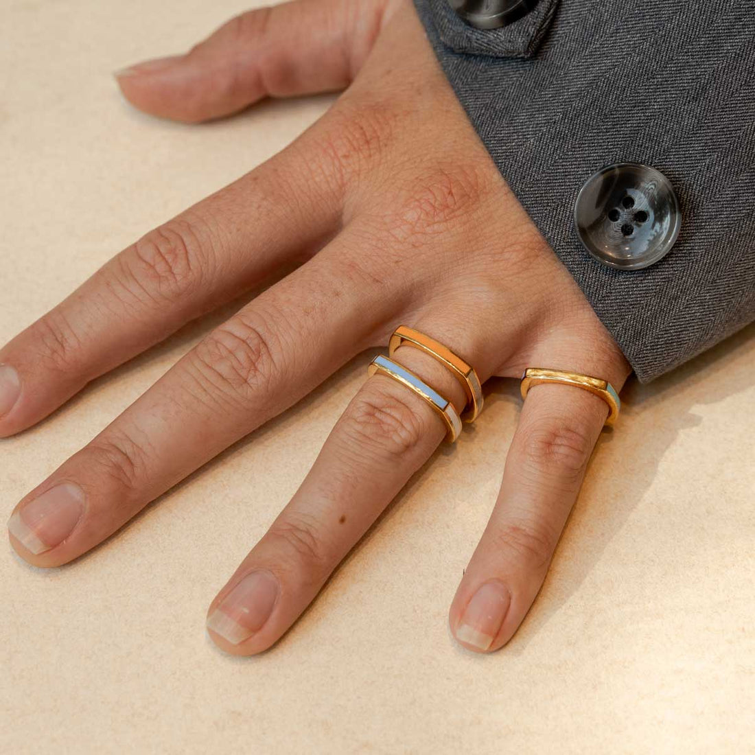 Model trägt drei quadratische Ringe in hellen Sommerfarben