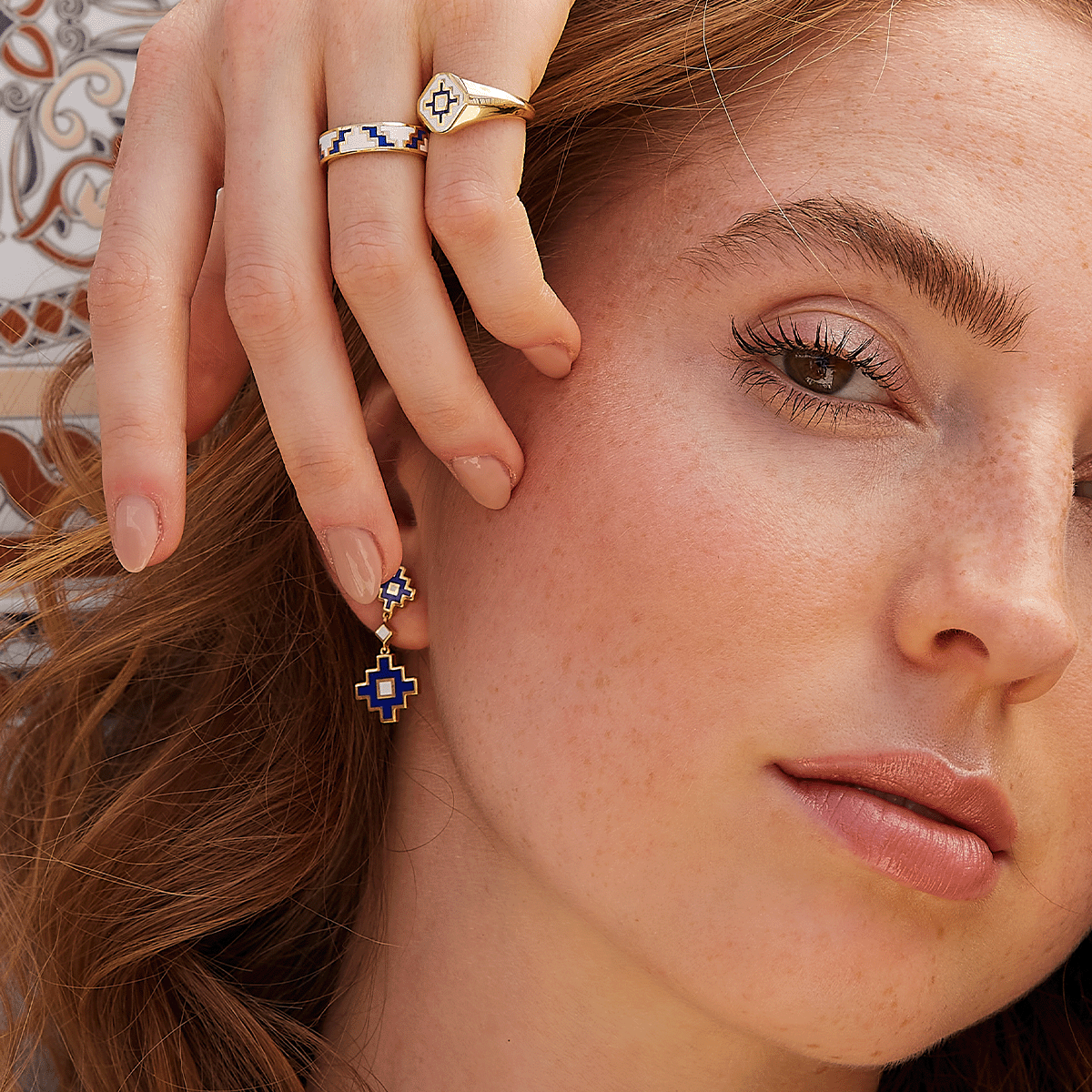 Model trägt vergoldeten Schmuck mit blau-weißen Keramikdetails